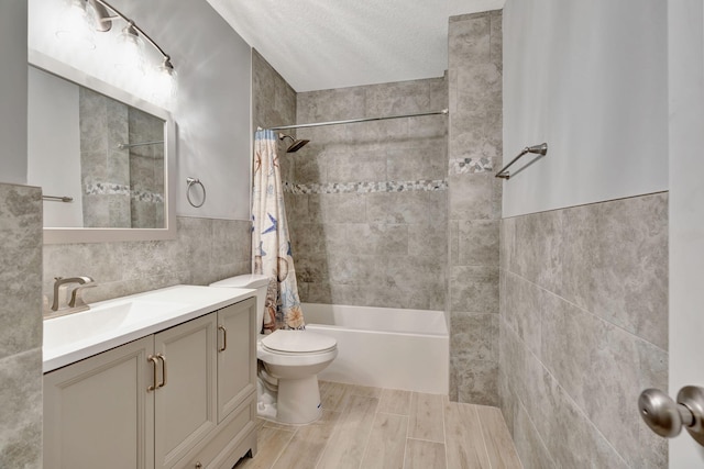 full bathroom featuring a textured ceiling, shower / bathtub combination with curtain, tile walls, toilet, and vanity