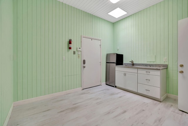 interior space with wood walls, light hardwood / wood-style floors, and sink