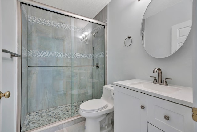 bathroom featuring toilet, a textured ceiling, walk in shower, and vanity