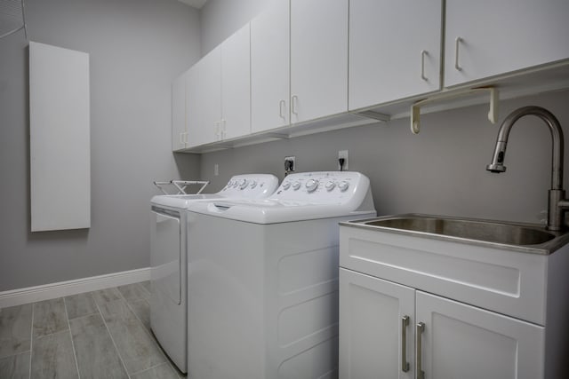 laundry area with cabinets, washing machine and dryer, sink, and light wood-type flooring