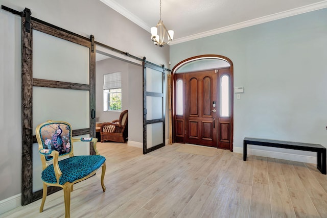 foyer featuring an inviting chandelier, crown molding, light hardwood / wood-style floors, and a barn door