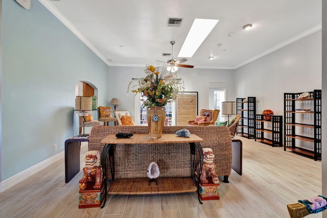 living room featuring ornamental molding, light wood-type flooring, and a skylight