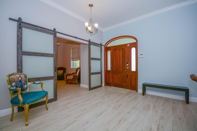 foyer with a notable chandelier, ornamental molding, a barn door, and light wood-type flooring