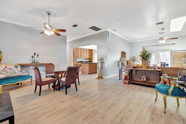 dining room featuring ornamental molding, light hardwood / wood-style flooring, a skylight, and ceiling fan