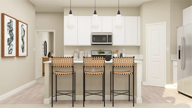 kitchen featuring appliances with stainless steel finishes, a breakfast bar, white cabinets, a center island, and hanging light fixtures