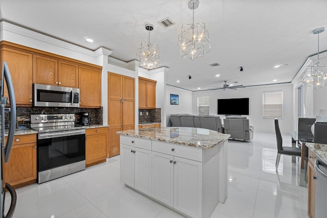 kitchen with decorative light fixtures, ceiling fan, appliances with stainless steel finishes, and crown molding