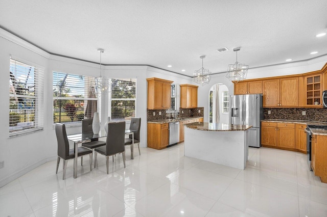 kitchen with hanging light fixtures, stainless steel appliances, and ornamental molding