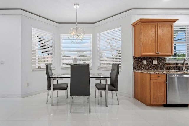 dining room with light tile patterned floors, sink, an inviting chandelier, and ornamental molding