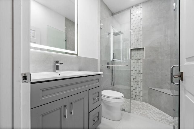 full bathroom with toilet, a stall shower, vanity, and tile walls