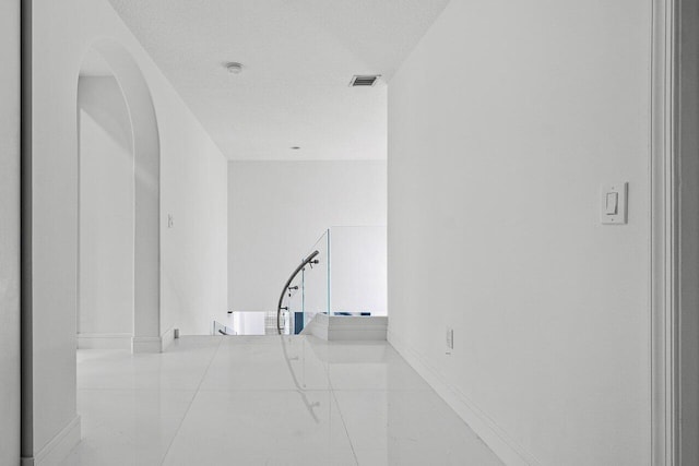 empty room featuring visible vents, arched walkways, and a textured ceiling