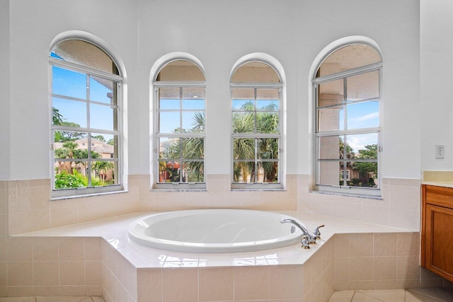 bathroom featuring a relaxing tiled tub and vanity