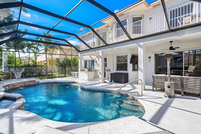 view of pool with ceiling fan, an outdoor kitchen, a patio, and a lanai