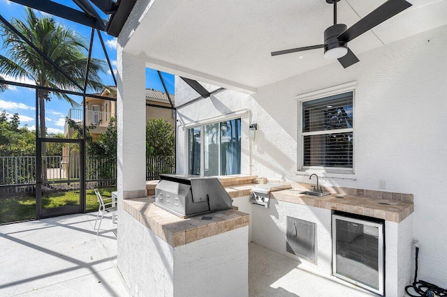 view of patio featuring ceiling fan, area for grilling, sink, an outdoor kitchen, and beverage cooler