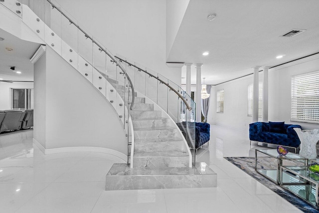 stairs with crown molding, tile patterned floors, and decorative columns