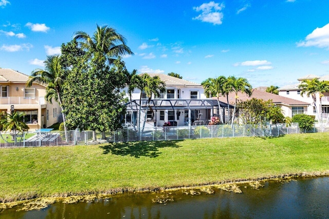 back of house featuring a water view, a yard, and a lanai