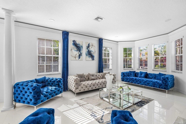 tiled living room with a textured ceiling, crown molding, and decorative columns