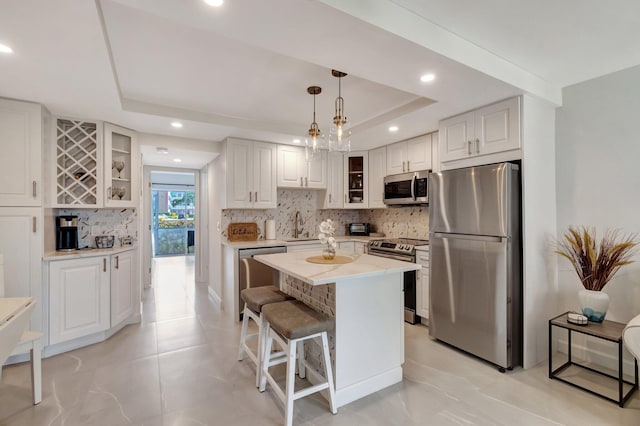 6 Lyndhurst A, Deerfield Beach, FL 33442 - kitchen with white cabinets, a kitchen island, stainless steel appliances, hanging light fixtures, and a tray ceiling