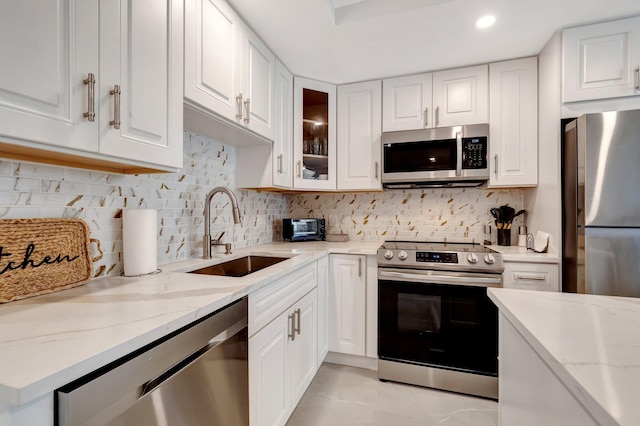 kitchen with light stone countertops, white cabinets, and appliances with stainless steel finishes