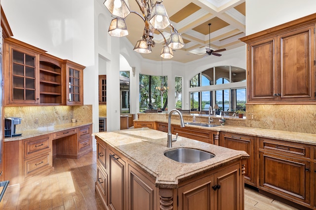 kitchen featuring sink, hanging light fixtures, coffered ceiling, a kitchen island with sink, and beam ceiling