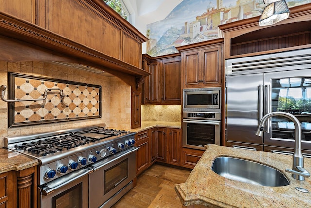 135 Playa Rienta Way, Palm Beach Gardens, FL 33418 - kitchen with built in appliances, a sink, tasteful backsplash, and light stone counters