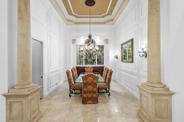 dining area with decorative columns, an inviting chandelier, ornamental molding, and a tray ceiling