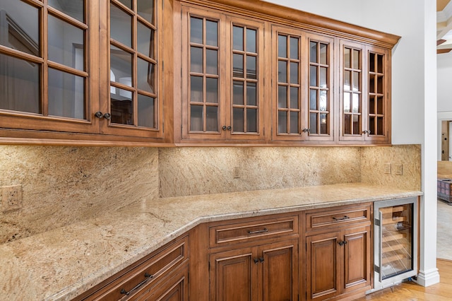 135 Playa Rienta Way, Palm Beach Gardens, FL 33418 - kitchen featuring wine cooler, brown cabinets, light stone countertops, and decorative backsplash