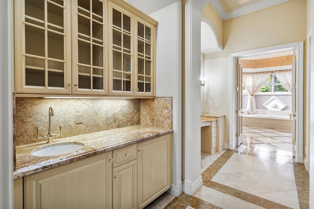 kitchen with sink, ornamental molding, light stone counters, and tasteful backsplash