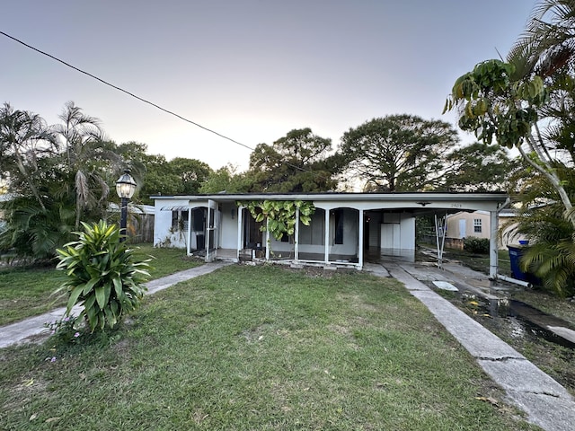 view of front of property featuring a carport and a lawn