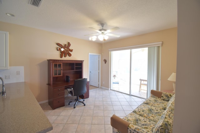 tiled office space featuring a textured ceiling and ceiling fan