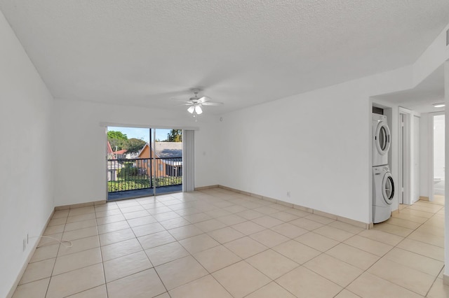 spare room with stacked washer / drying machine, ceiling fan, light tile patterned floors, and a textured ceiling