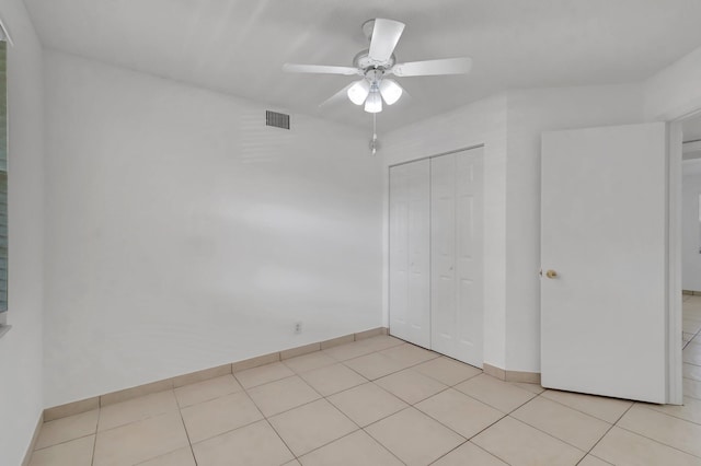 unfurnished bedroom with light tile patterned floors, a closet, and ceiling fan