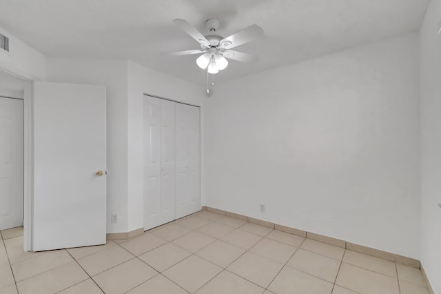 unfurnished bedroom with light tile patterned floors, a closet, and ceiling fan