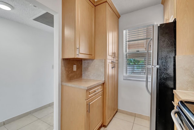 kitchen with appliances with stainless steel finishes, light tile patterned floors, and light brown cabinetry