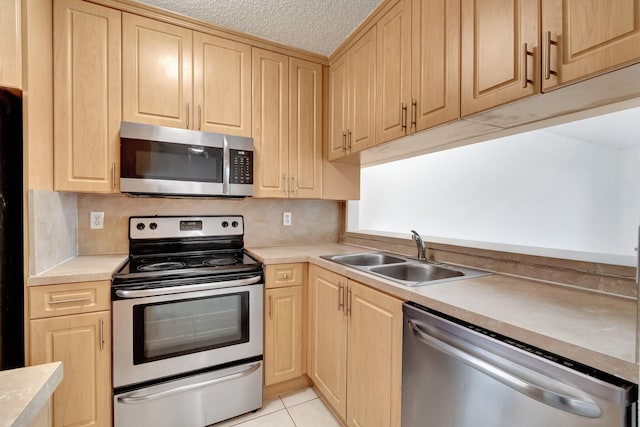 kitchen featuring light brown cabinetry, light tile patterned floors, sink, and appliances with stainless steel finishes