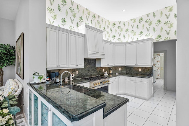 kitchen featuring sink, stainless steel stove, white cabinets, and kitchen peninsula