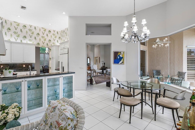 dining room with light tile patterned floors, a chandelier, a towering ceiling, and sink