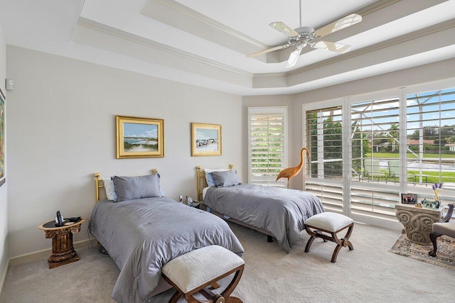 carpeted bedroom featuring ceiling fan, crown molding, and a tray ceiling