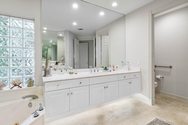 bathroom featuring toilet, a bathing tub, a healthy amount of sunlight, and vanity