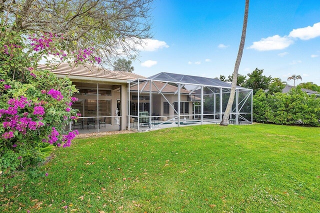 rear view of property with ceiling fan, a lanai, a yard, and a swimming pool