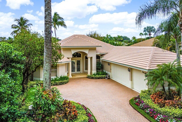 mediterranean / spanish house with a garage and french doors