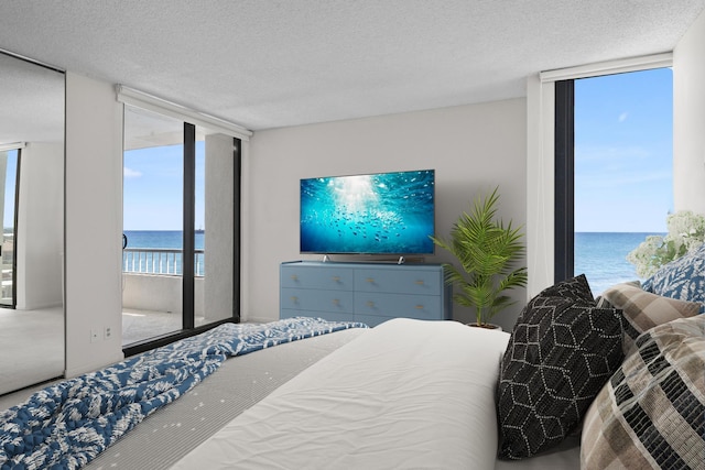 bedroom with a textured ceiling, access to outside, and floor to ceiling windows