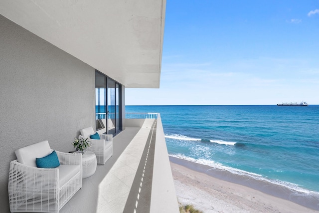 balcony featuring a beach view and a water view