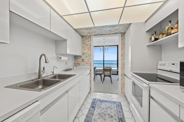 kitchen with sink, white cabinets, an inviting chandelier, a water view, and white appliances