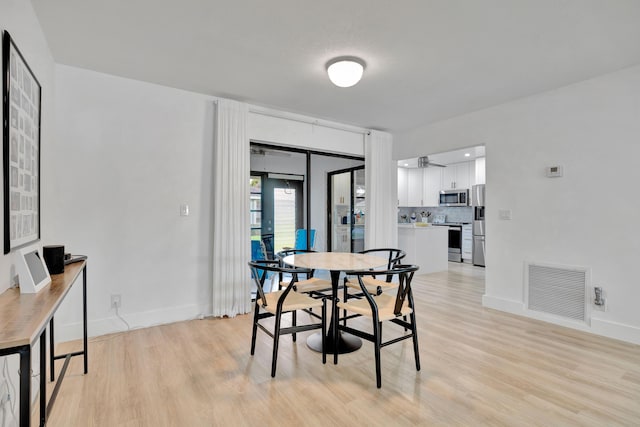 dining room with light hardwood / wood-style floors and french doors