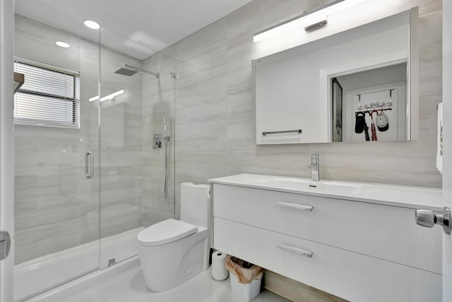 bathroom featuring tile walls, a shower with door, vanity, and toilet