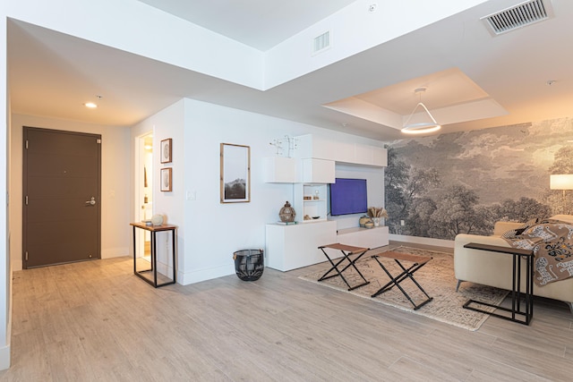 living room with a raised ceiling and light hardwood / wood-style floors