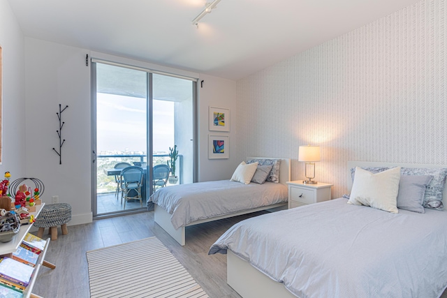 bedroom with rail lighting, light hardwood / wood-style flooring, and access to exterior