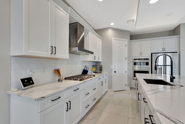 kitchen with white cabinets, wall chimney range hood, appliances with stainless steel finishes, and sink