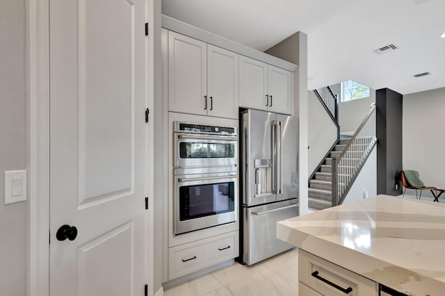 kitchen featuring white cabinets, appliances with stainless steel finishes, and light stone counters