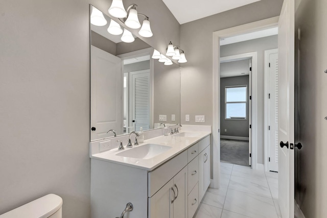 bathroom featuring toilet, vanity, and a notable chandelier